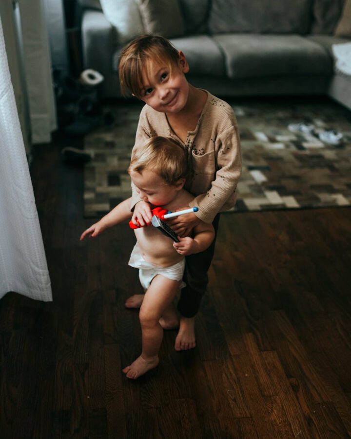 older brother wrapping arms around younger brother near the couch